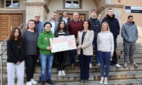 Auf dem Bild halten Kindertafel-Botschafterin Steffi List (grünes Oberteil) und Schulleiterin Ulrike Hoch den Scheck, dazwischen Klassensprecherin Zerin Belal, rechts Klassenlehrerin Anja Schölch. Links neben List und darüber gegen den Uhrzeigersinn Projektleiterin und Lehrerin Tina Sauer und zwischen den Kindertafel-Vorständen Stefan Labus und Rainer Zink steht Alexander Kuckshaus, Center-Manager der Stadtgalerie Schweinfurt. Foto: Michael Horling